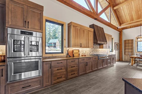 A clockwise tour around the kitchen island starts with a large stainless steel refrigerator and freezer with an ice maker, followed by two wall ovens and a six-burner gas range, providing ample space for culinary creations.