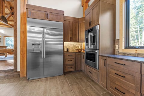 A clockwise tour around the kitchen island starts with a large stainless steel refrigerator and freezer with an ice maker, followed by two wall ovens and a six-burner gas range, providing ample space for culinary creations.