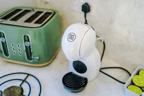 The kitchen is fully equipped with modern appliances, including a coffee machine, making it a perfect space for preparing meals and enjoying your morning brew. It offers ample counter space and storage, ideal for both cooking and casual dining.