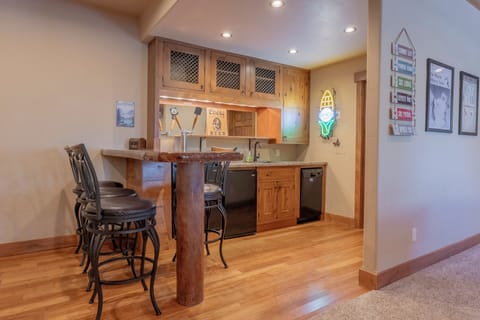 The lower-level wet bar offers a mini fridge, dishwasher, and a pub-like space.