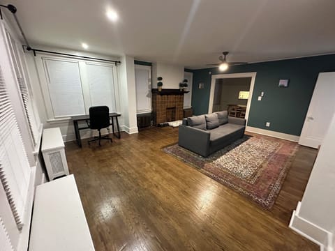 Large living room with desk, pull-out couch, Roku TV, powder room, ceiling fan.