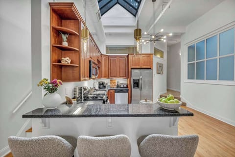Stylish and inviting kitchen featuring rich wood cabinetry, polished granite countertops, and a skylight that bathes the space in natural light. Ideal for savoring meals or a morning coffee at the comfortable breakfast bar!