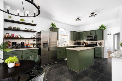 Cook and gather in this spacious, fully equipped kitchen featuring stylish green cabinetry, modern appliances, and an inviting dining area—perfect for shared meals and memorable moments!