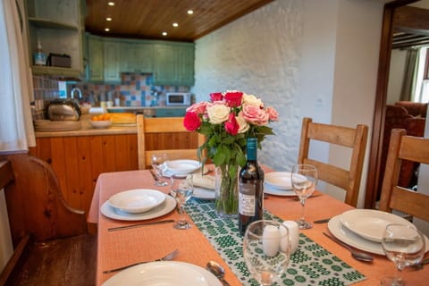 Dining table laid for dinner with a vase of flower and a bottle of wine
