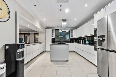 A sleek, modern kitchen with white cabinetry, stainless steel appliances, and a central island.