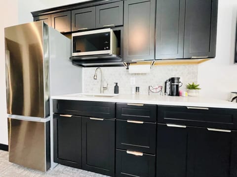 Stylish kitchen with dark cabinetry, stainless steel appliances, and a well-appointed coffee station for your morning needs.