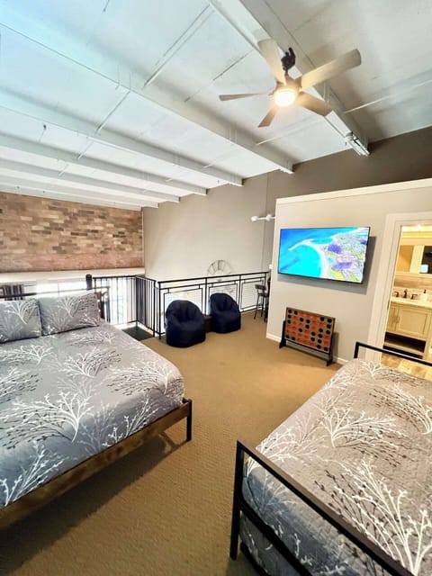 The loft area features a spacious layout with a cozy bean bag seating, and a mounted flat-screen TV, creating a relaxing and versatile space for lounging or sleeping.