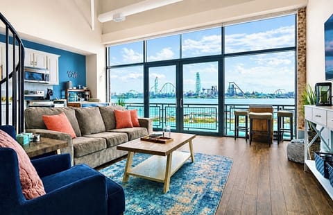 Spacious and stylish living room featuring a spiral staircase, open kitchen layout, and floor-to-ceiling windows that flood the space with natural light.