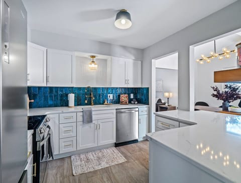 House two: A culinary haven, bathed in the vibrant hues of teal.  The pristine white cabinetry and gleaming appliances create a sophisticated backdrop. 🍳 #ModernKitchen