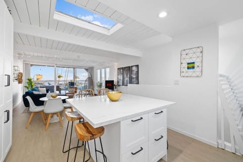 A modern, bright kitchen with a spacious marble island that doubles as a breakfast bar with unique wooden stools.
