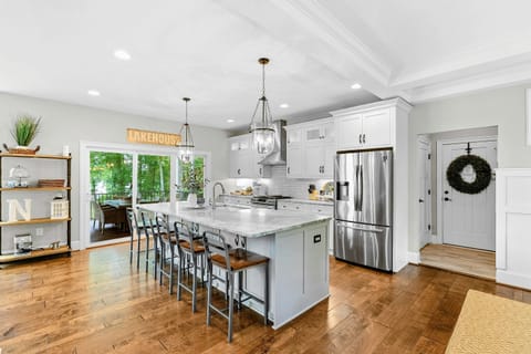A spacious and modern kitchen with a large marble island, high-end appliances, elegant pendant lighting, and open access to the dining and living areas with views of the backyard.