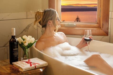 Unwind in a bubbly bath with wine, enjoying stunning sunset views