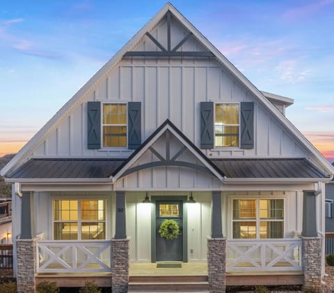 - Step into your storybook escape, glowing with warmth and charm as twilight falls
- Timeless farmhouse design meets rustic stonework and a cozy front porch made for lingering
- Serene, private haven in a scenic lakefront community