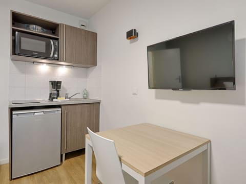 Fully equipped studio kitchenette with an electric hob, microwave, and compact dining area, perfect for independent travelers.
