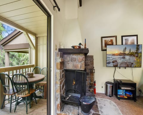 Living room with Smart TV, wood burning fireplace, and balcony access