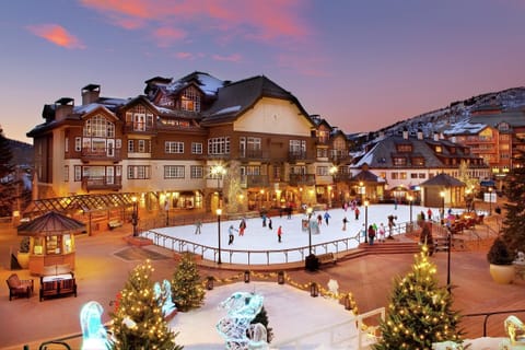 Enchanting village scene with a festive ice skating rink, twinkling lights, and a magical alpine atmosphere.