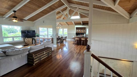 - Open concept design connects living room dining and kitchen - Vaulted ceilings and hardwood floors enhance tropical feel - Bright windows invite natural light throughout the space