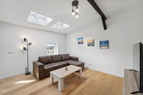 Das helle Wohnzimmer unter Dachfenstern besticht mit einer gemütlichen Couch, einem modernen Holztisch und stilvoller Wanddeko für entspannte Stunden.