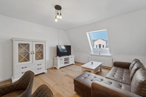 Helles Wohnzimmer mit gemütlichem Sofa, TV und modernem Schrank – perfekt zum Entspannen.