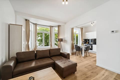 Offener Wohn- und Essbereich mit gemütlichem Sofa, viel Tageslicht und direkter Anbindung an die moderne Küche.