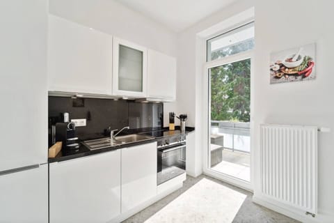 Die moderne Küche in Wilhelmshaven überzeugt mit stilvollen Hochglanzfronten, schwarzer Arbeitsplatte, kompletter Ausstattung und direktem Zugang zum Balkon.