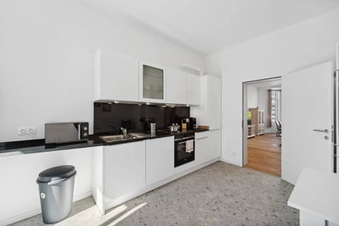 Die moderne Küche in Wilhelmshaven ist mit weißen Hochglanzfronten, schwarzer Arbeitsplatte, vollständiger Ausstattung und direktem Zugang zum Wohn- und Essbereich eingerichtet.