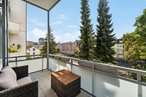 Der Balkon bietet gemütliche Sitzgelegenheiten und einen schönen Ausblick auf die Nachbarschaft mit viel Grün und charmanten Altbauten.