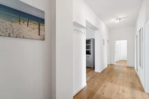 Der helle Flur in Wilhelmshaven ist mit freundlichem Holzfußboden, Wandgarderobe und modernen Details ausgestattet und bietet Zugang zu den Wohn- und Schlafräumen.