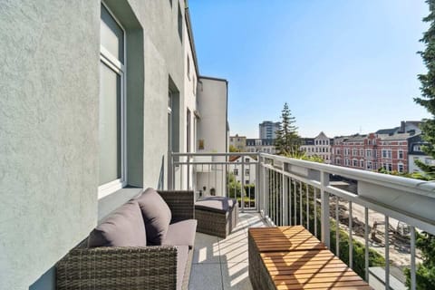 Der sonnige Balkon lädt mit gemütlichen Sitzmöbeln und Blick auf die Nachbarschaft zum Entspannen ein.