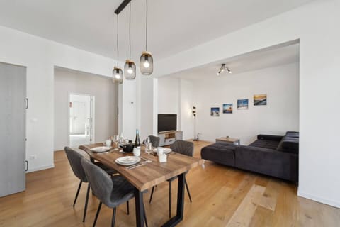 Das stilvolle Esszimmer mit rustikalem Holztisch geht harmonisch in den gemütlichen Wohnbereich mit großer Couch und TV über.