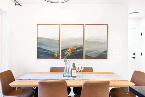 This cozy dining space is designed for gathering with loved ones. The warm wooden table, paired with elegant leather chairs, creates an inviting atmosphere. The large wall art behind the table adds a serene touchbringing a sense of calm to your meal.