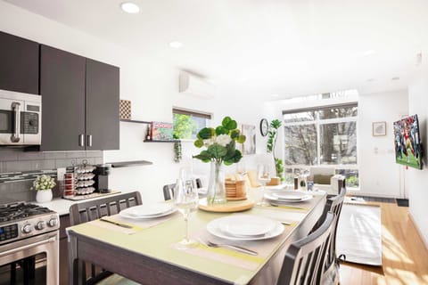 Dine in style! This beautifully set dining space offers an intimate atmosphere with elegant tableware, lush greenery, and an open layout for a memorable mealtime experience.