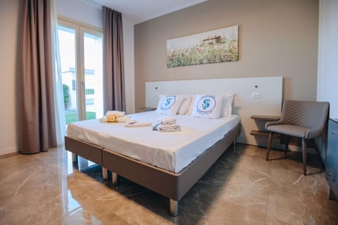 Modern double room with direct access to the garden, located in the Ranalli Palace residence in Peschiera del Garda, a short walk from the Pederzoli Hospital. Furnished in a contemporary style with neutral colors, it offers comfort, brightness, and tranquility for a relaxing stay on Lake Garda.