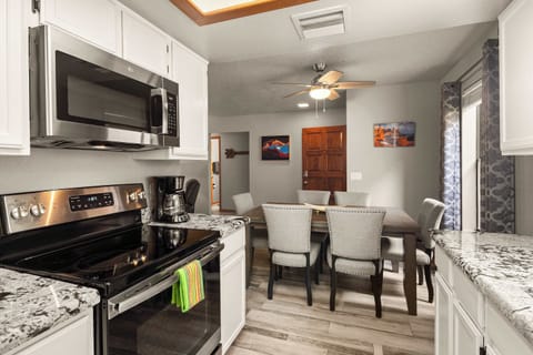 Modern kitchen and dining area with stylish granite countertops, light gray chairs, and a welcoming atmosphere.