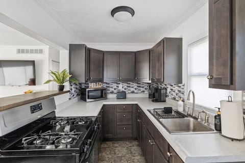 This updated kitchen has a stove, refrigerator, microwave, toaster, crock pot, Keurig coffee maker and a variety of spices.