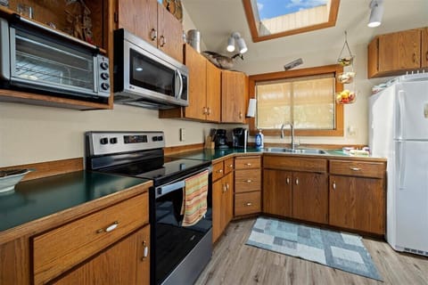 Kitchen with electric stove, microwave, toaster over and standard amenities.