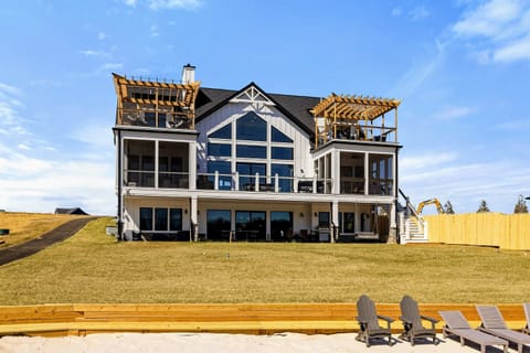 Elegant Lakefront Home: A breathtaking three-story retreat featuring expansive windows, multiple balconies with pergolas, and seamless indoor-outdoor living, all overlooking a private sandy beach and Lake Anna.