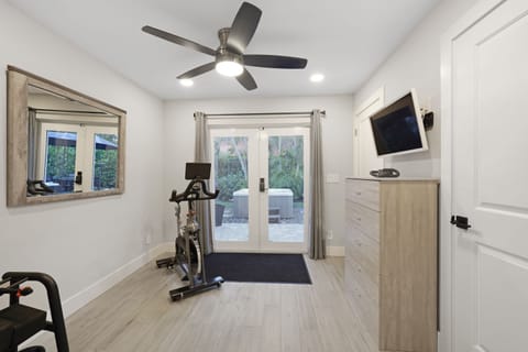 A bright and airy workout space featuring an exercise bike, full-length mirror, and French doors leading to the backyard—perfect for an energizing workout.