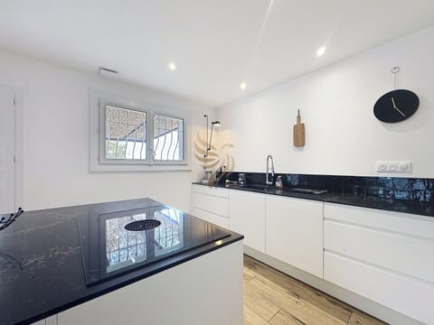 La cuisine accueille un îlot central idéal pour cuisiner ensemble, avec des surfaces de marbre noir faciles à nettoyer, parfait pour préparer un repas convivial.