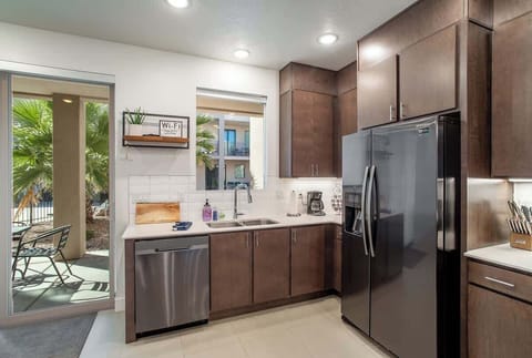 Bright and modern kitchen with stainless steel appliances, dark wood cabinetry, and a sliding door leading to the furnished back patio.