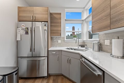 A modern kitchen with stainless steel appliances, wood-accented cabinets, and bright natural light, fully stocked with supplies.