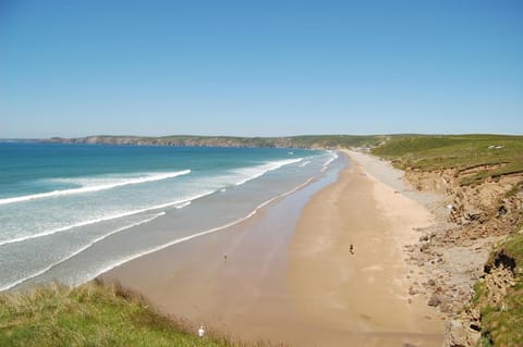 Very long stretch of sand at Newgale beach with dunes and cliffs on right sea on left