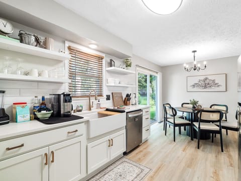 Bright & breezy kitchen with open shelving, a farmhouse sink, and everything you need to cook up a storm 🍽️🌿. Slide open the doors and enjoy meals with a view in the stylish dining nook! 🪟