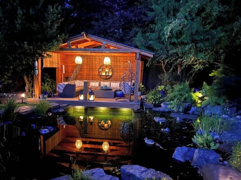 The dock at night with lights in the swim pond, and propane fire table.