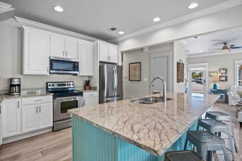 Beach Please - Modern kitchen featuring an island bar with seating