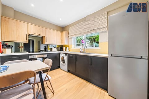 A beautifully designed kitchen with a modern touch! Featuring sleek black and wood cabinetry, built-in appliances, and a cosy dining area—perfect for cooking and enjoying meals in style.