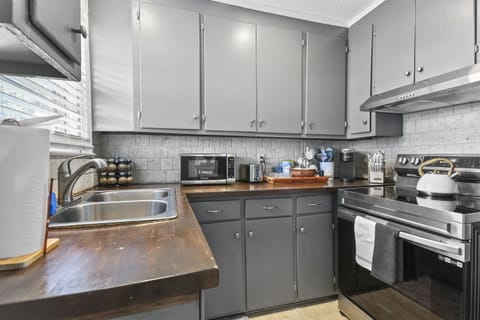 The kitchen blends style and function with its warm wood countertops, modern appliances, and cozy charm.