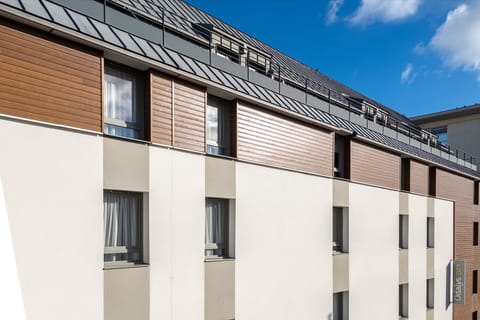 The building's clean lines and minimalistic façade highlight a blend of urban sophistication, with large windows allowing natural light to flood into the stylishly arranged apartments.