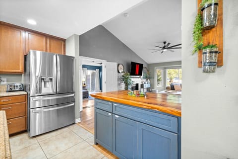 Modern kitchen with stainless steel appliances, wood island, and open views to the living room.
