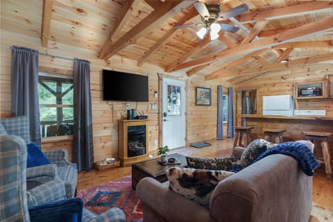 Cozy up in this charming cabin living room 🛋️🔥. Featuring warm wood finishes, a comfy sofa, and an electric fireplace under vaulted ceilings—perfect for movie nights or simply unwinding in rustic comfort 🌲📺